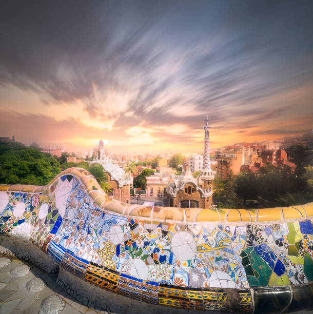 View of mosaic tile and Barcelona cityscape in famous park Guell at summer sunset, Spain