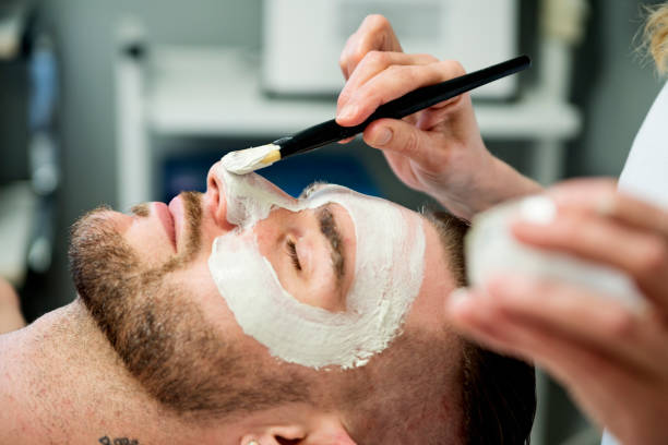 jeune homme recevant un soin du visage au spa beauté. - facial mask spa treatment health spa human face photos et images de collection