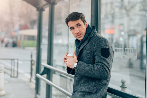 istock Young man holding coffee cup on a bus station 944818738