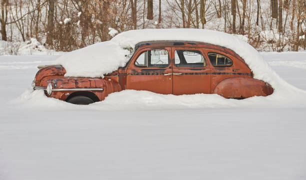 rusted antique Plymouth four-door car in heavy snow drift