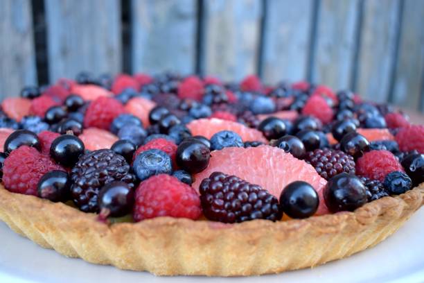 istock Close up Fruit Tart Dessert Homebaked Fresh Raspberry Blueberry Grapefruit Summer Berries. Homemade Cake. Top view. Wooden Rustic Background 944825986