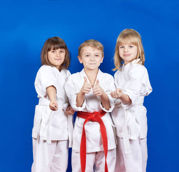 istock Three children standing in karate rack and showing finger super 944830936