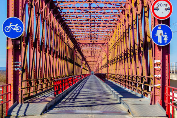 istock Red iron bridge crossing a river with roadway. 944834904
