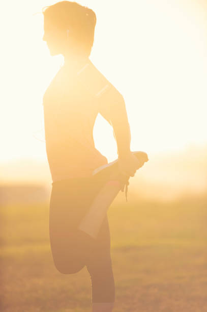 silhouette d’une femme qui s’étend dans le parc. - distance running jogging running fog photos et images de collection