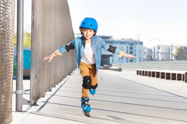 Photo of Smiling boy practicing rollerskating at rink