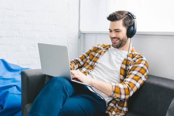 istock Man in headphones working on laptop in light office 944846560