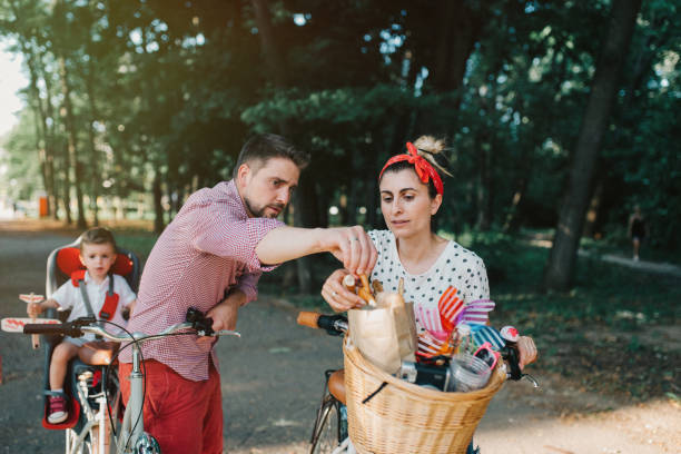 Young family eating breadsticks while riding bicycles in the park