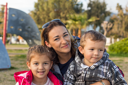 Happy family outdoors. Beautiful smiling mom with children two kids - girl and boy. Shot with shallow depth of field.