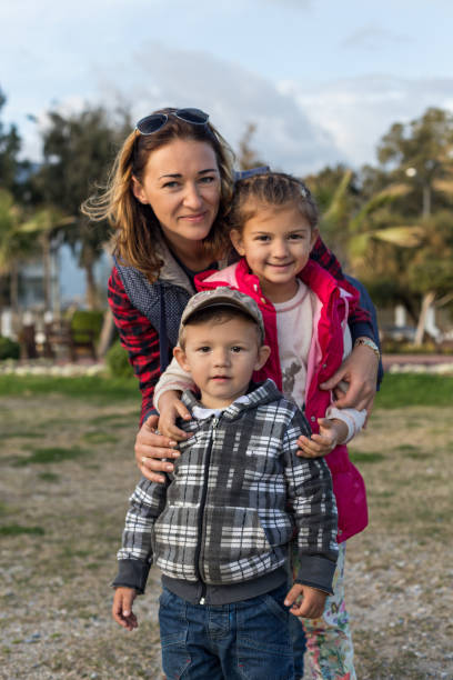 Happy family outdoors. Mom with two toddlers.