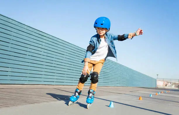 Photo of Boy learning to roller skate on road with cones