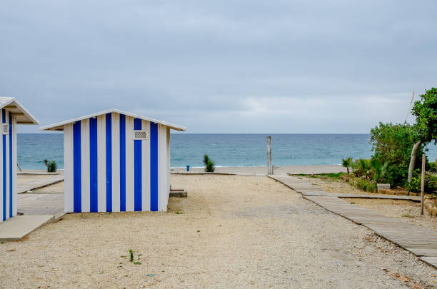 istock Blue striped beach hut in the sand 944855556