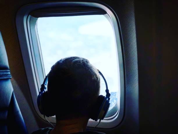istock Little boy looking out of plane window 944860672