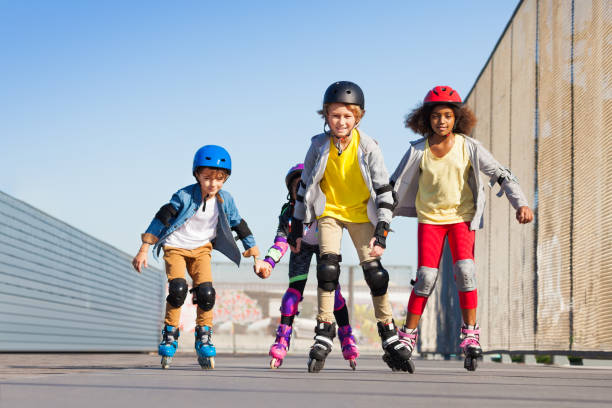 Boys and girls rollerblading at stadium outdoors Group of preteen multiethnic boys and girls rollerblading together at stadium outdoors inline skating stock pictures, royalty-free photos & images
