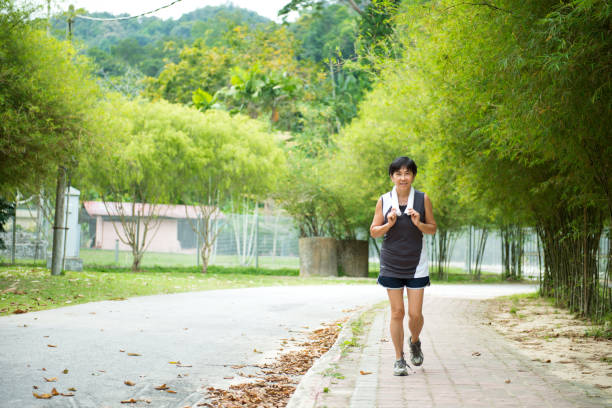 istock Front view of senior woman jogging through park 944868912