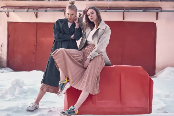 Photo of Couple beautiful hipster girls wearing long fashion coats on the street