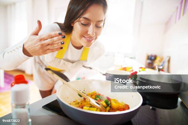 Young Charming Pretty Woman Is Smiling While Smelling The Aroma Of Her Fresh Healthy Breakfast Being Cooked Stock Photo - Download Image Now