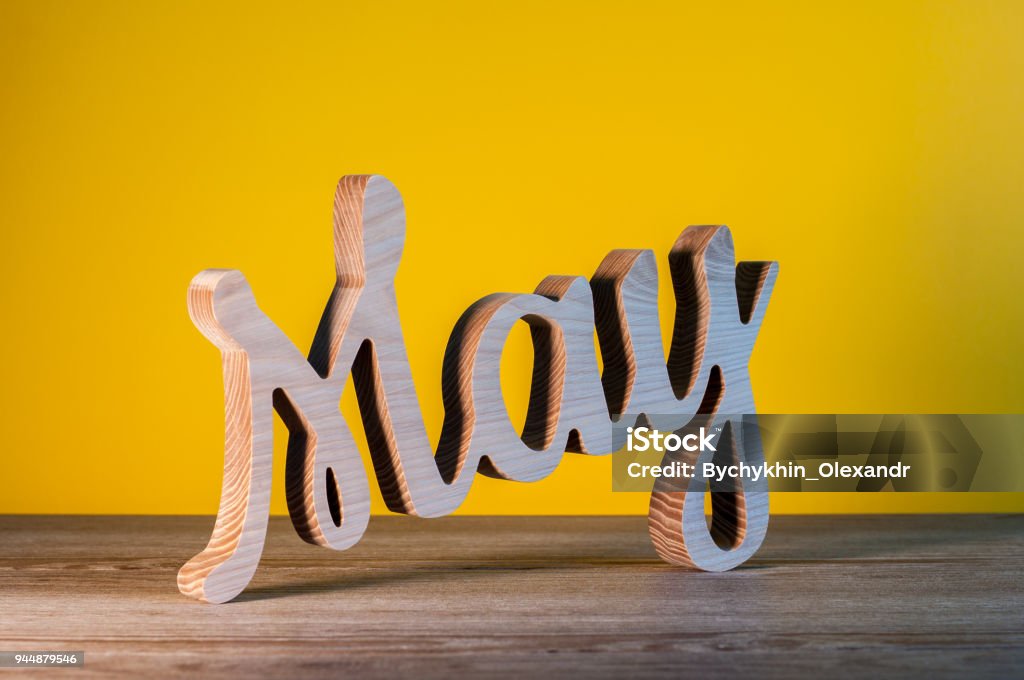 May -wooden carved name of spring month. Calendar on business office table, workplace at yellow background. Spring time May -wooden carved name of spring month. Calendar on business office table, workplace at yellow background. Spring time. April Stock Photo