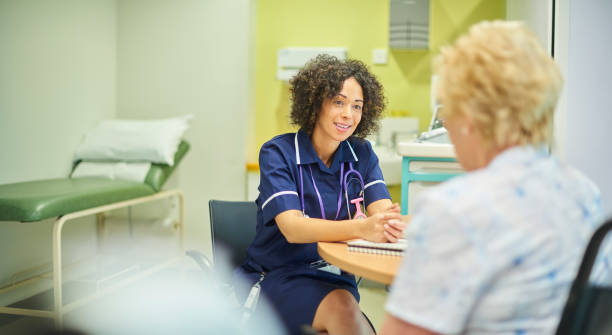 nurse at walk-in centre a female nurse talks to a senior patient in the clinic triage triage stock pictures, royalty-free photos & images