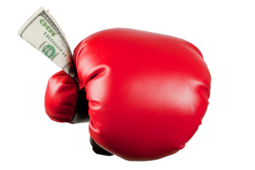 Boxing gloves holds a US dollar bill. Fighting sports and martial arts winning prize money concept. White background.