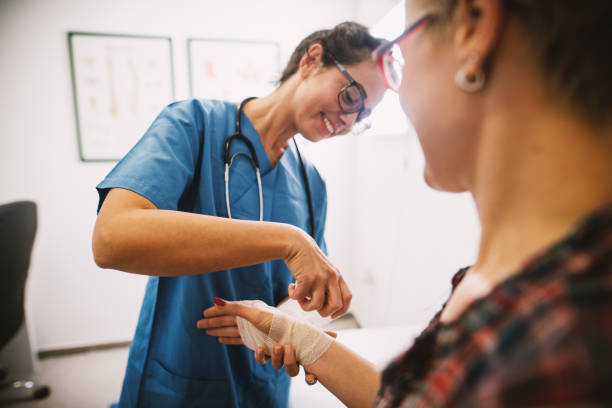 enfermera profesional en el hospital vendado la mano con un vendaje médico para un paciente mujer. - muñeca articulación fotografías e imágenes de stock