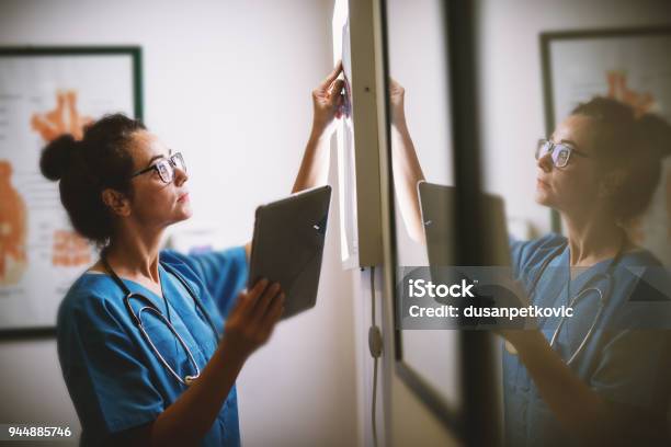 Photo libre de droit de Vue Latérale Du Sourire Milieu Ans Infirmière Contrôle Aux Rayons X Dans Un Docto banque d'images et plus d'images libres de droit de Suivi des malades