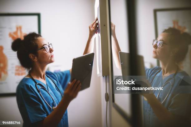 Vista Laterale Dellinfermiera Sorridente Di Mezza Età Che Controlla Le Radiografie In Un Docto - Fotografie stock e altre immagini di Infermiere