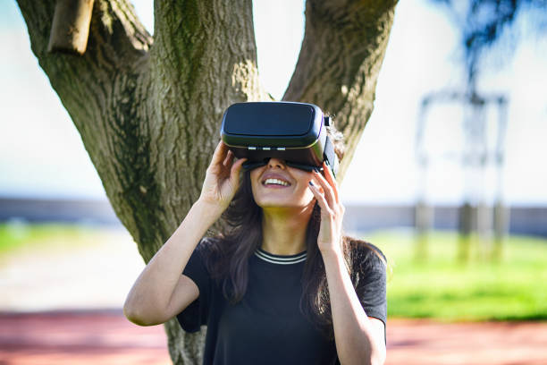istock Young woman leaning on the tree,looking around via VR 944889372