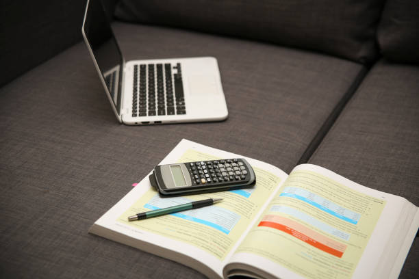 istock Studying on the coach. White laptop with a book, and a calculator 944889620