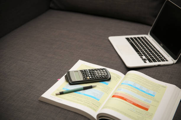 istock Studying on the coach. White laptop with a book, and a calculator 944889644