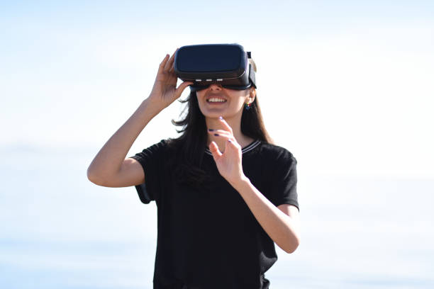 istock Young woman at the sea side looking around via VR 944893638