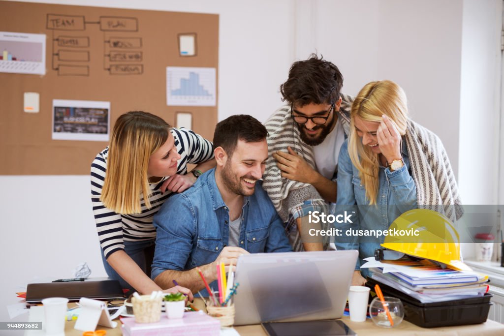 Equipo de negocio feliz hermosa joven mirando portátil mientras ríe y lluvia de ideas sus ideas. - Foto de stock de Inmobiliaria libre de derechos