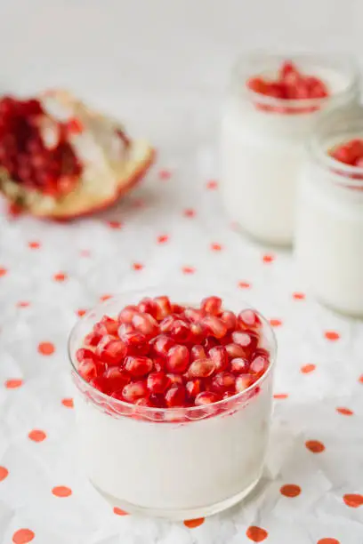 Homemade yogurt with pomegranate seeds in a glass jar, on a paper napkin in peas