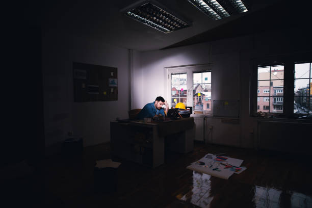 istock Young tired disappointed business man searching for problem solution on a laptop while staying after regular working time in the dark office. 944906572