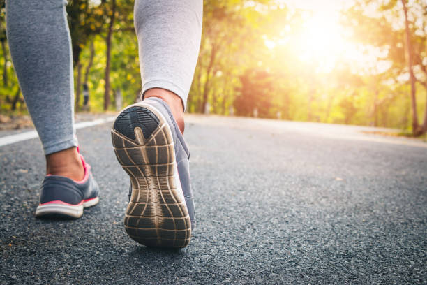 istock Women runner feet on road in workout wellness concept. 944914690