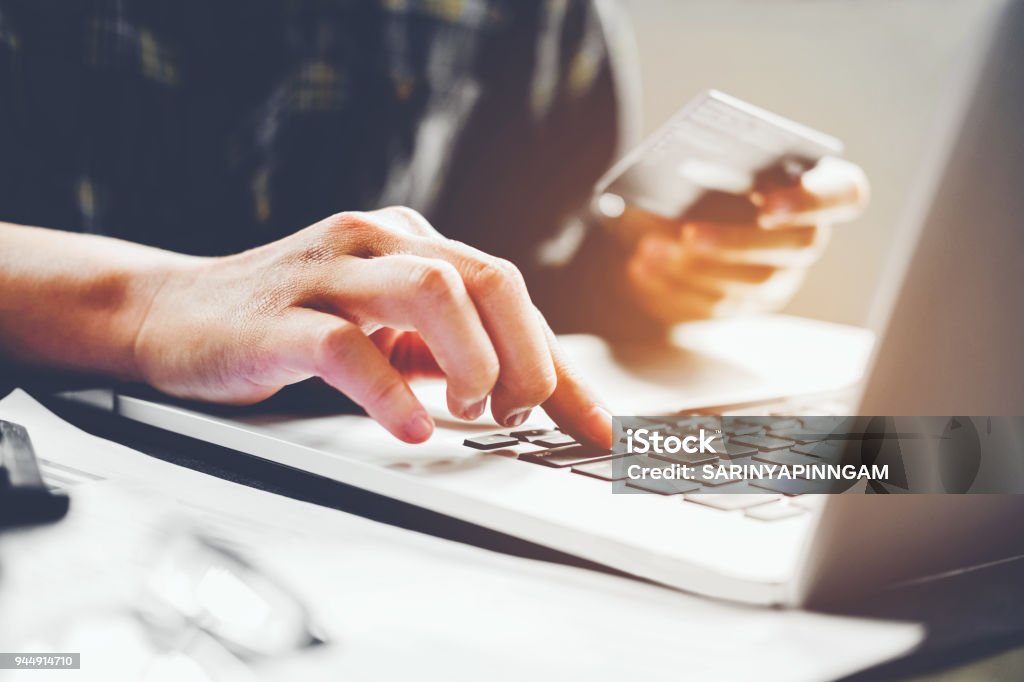 Man's hands typing laptop keyboard and holding credit card online shopping concept Paying Stock Photo