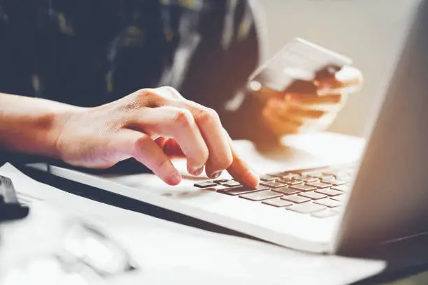 Man's hands typing laptop keyboard and holding credit card online shopping concept