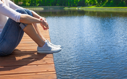 Woman relaxing lake side on wooden dock. People getaways, and enjoying nature concept.