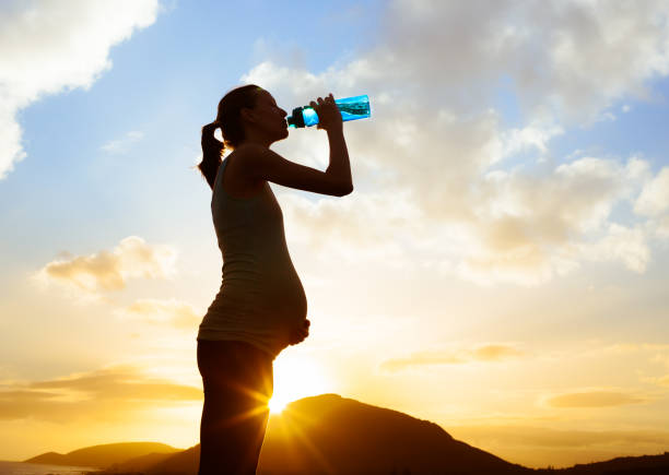 Silhouette of pregnant woman drinking water.