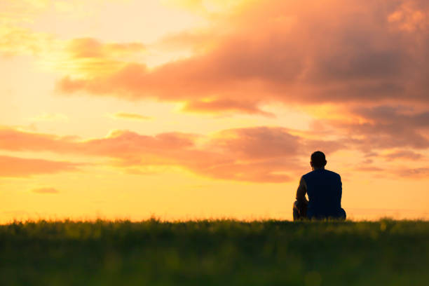 człowiek siedzący oglądając zachód słońca - osamotnienie zdjęcia i obrazy z banku zdjęć