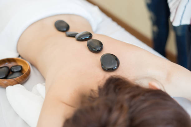 Young beautiful woman getting hot stone massage in spa salon. \