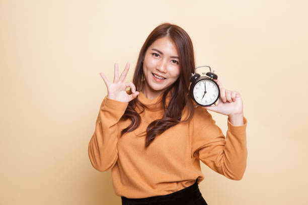 istock Young Asian woman show OK with a clock. 944936948