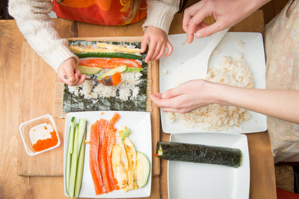 mutter und tochter machen sushi gerollt - sushi japanese culture food domestic kitchen stock-fotos und bilder