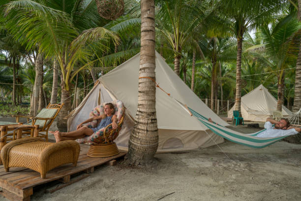 istock Young couple relaxing in glamping campground in tropical scenery 944945838