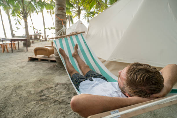 istock Young man relaxing on hammock in glamping campground 944946196