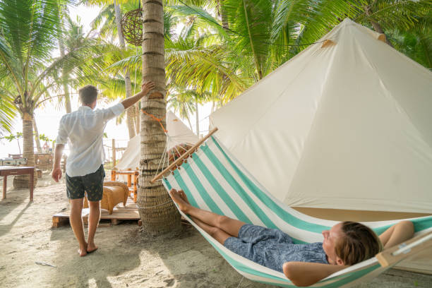 istock Young couple relaxing in glamping campground in tropical scenery 944946500