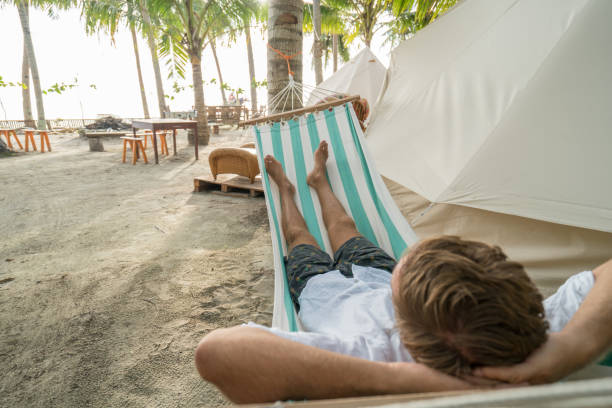 istock Young man relaxing on hammock in clamping campground 944946518
