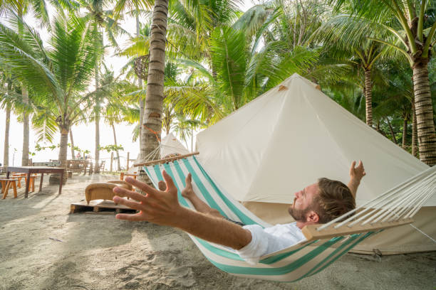 Man relaxing on hammock in clamping campground arms outstretched