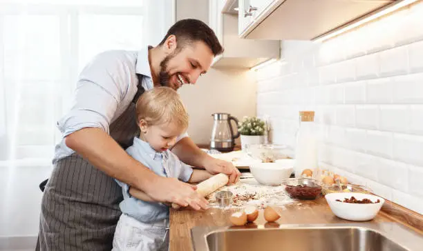 Photo of happy family in kitchen. father and child baking cookies