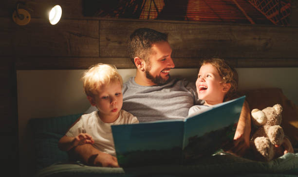 저녁 가족을 읽고입니다. 아버지는 아이 들을 읽습니다. 침대로 이동 하기 전에 서 - dark little girls child happiness 뉴스 사진 이미지