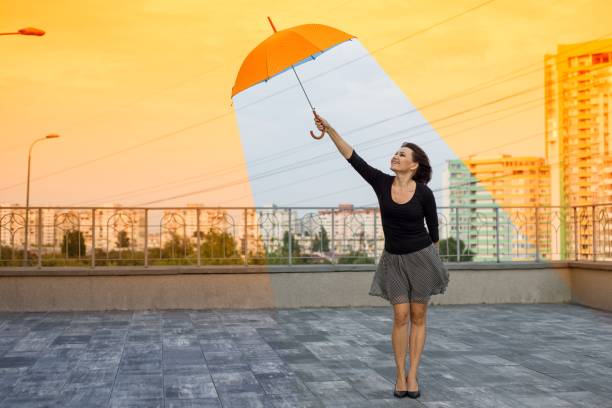 In hot weather, a young businesswoman uses an umbrella on her way to the office, checking the time during a working day. Her resolute look and makeup highlight her dedication to success.